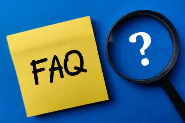 FAQ written on a note beside a magnifying glass with question mark