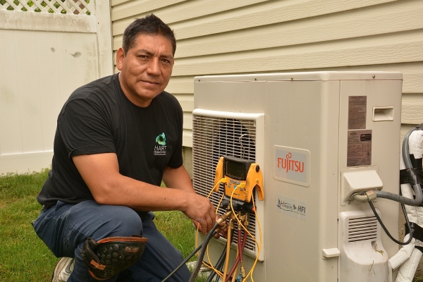 Hart Home Comfort Expert Technician assessing outdoor AC unit for replacement