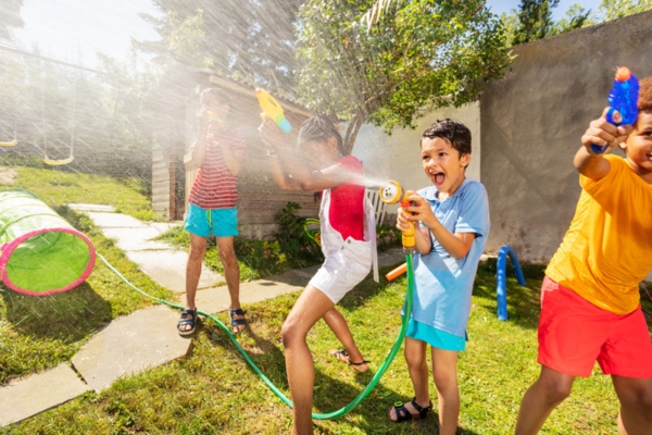 kids playing with water hose and water gun to stay cool under the summer heat due to AC breakdown