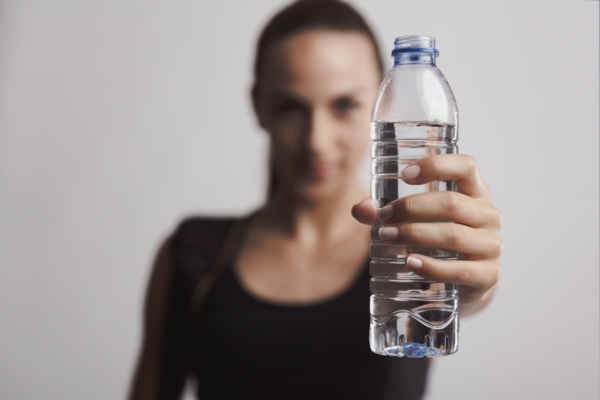 woman holding bottled water depicting staying hydrated to prevent heat exhaustion