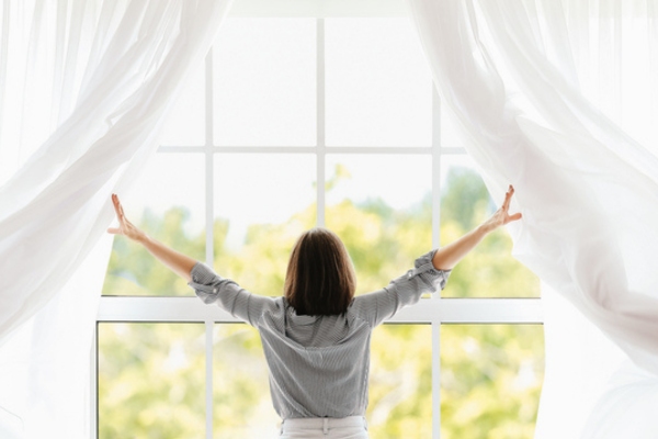 woman opening window during the day to let air circulate