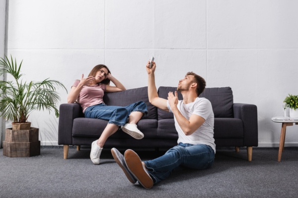 couple feeling warm and sweating while indoors depicting broken air conditioner needing replacement