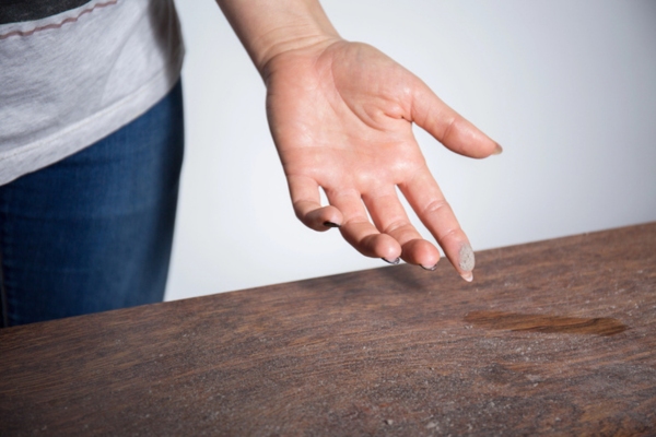 homeowner checking dust buildup on table