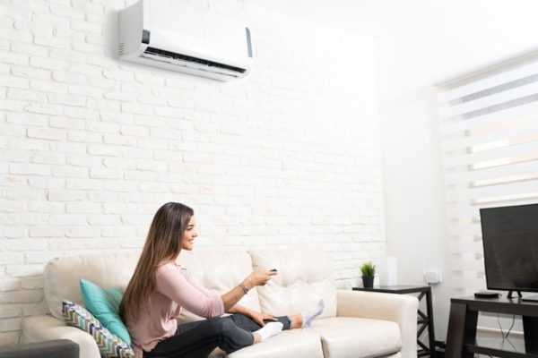 woman lounging & watching TV in the living room while keeping cool with a ductless air conditioner