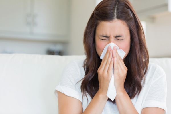 woman sneezing on tissue depicting poor indoor air quality