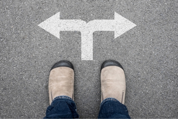 image of a person's shoes standing by two opposite arrows depicting deciding between air handler vs furnace