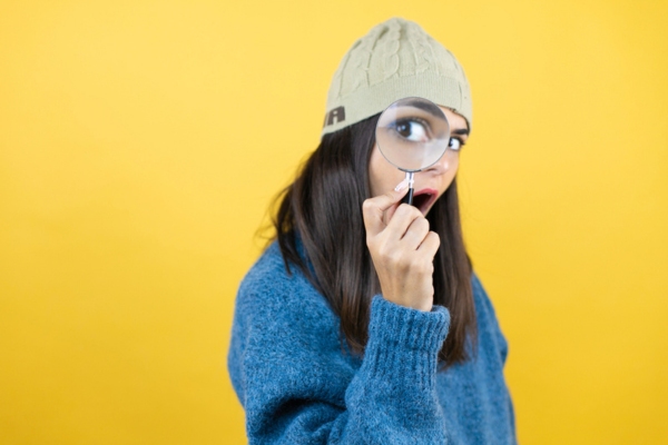 woman holding magnifying glass on her eye depicting identifying furnace noise concerns