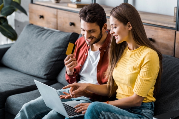 couple holding a credit card and laptop enrolling for automatic oil delivery