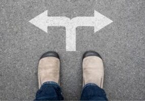 image of a person's shoes standing by two opposite arrows depicting deciding between air handler vs furnace