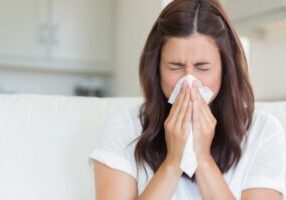 woman sneezing on tissue depicting poor indoor air quality